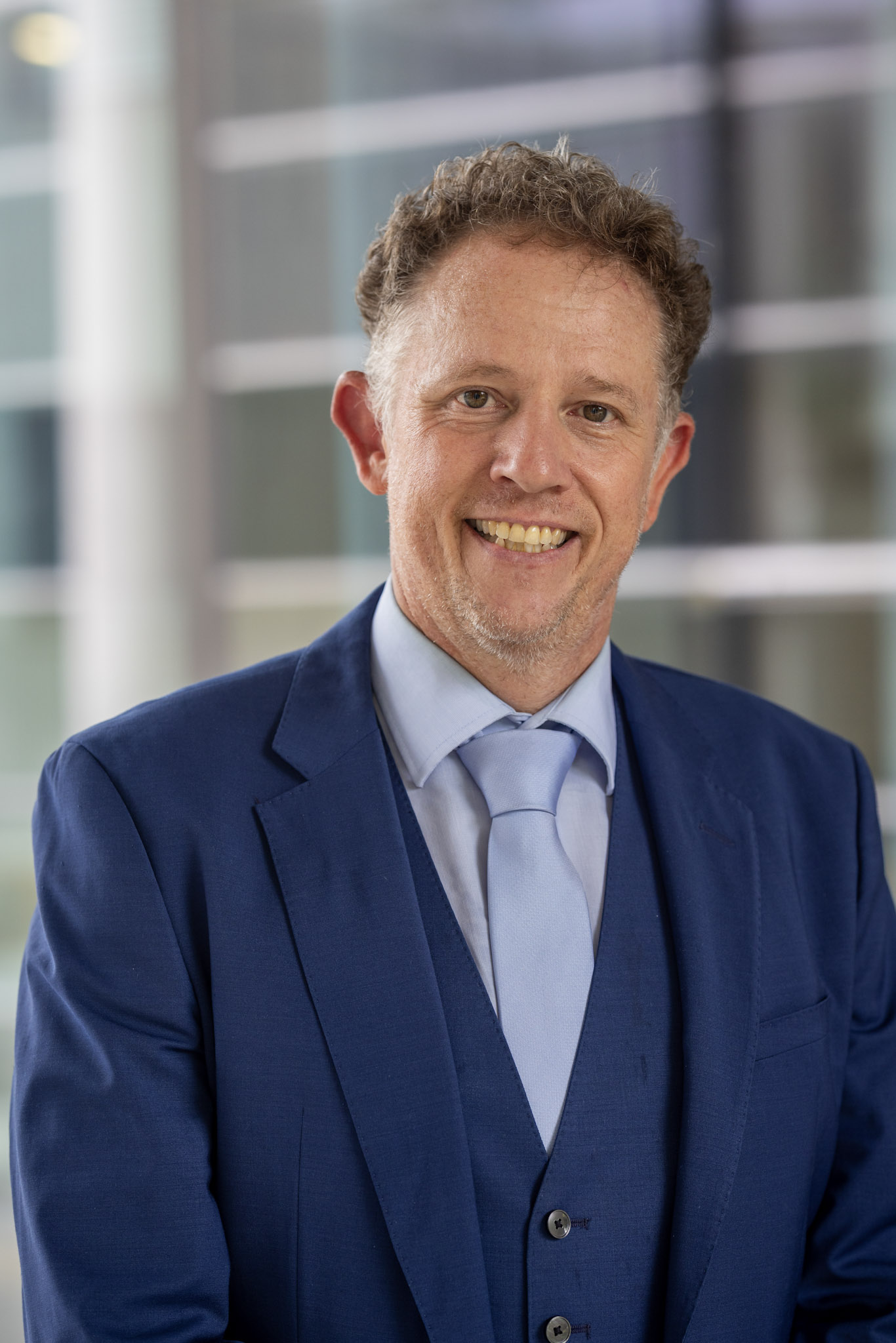 Peter Obermüller in Anzug und Krawatte, lächelnd.