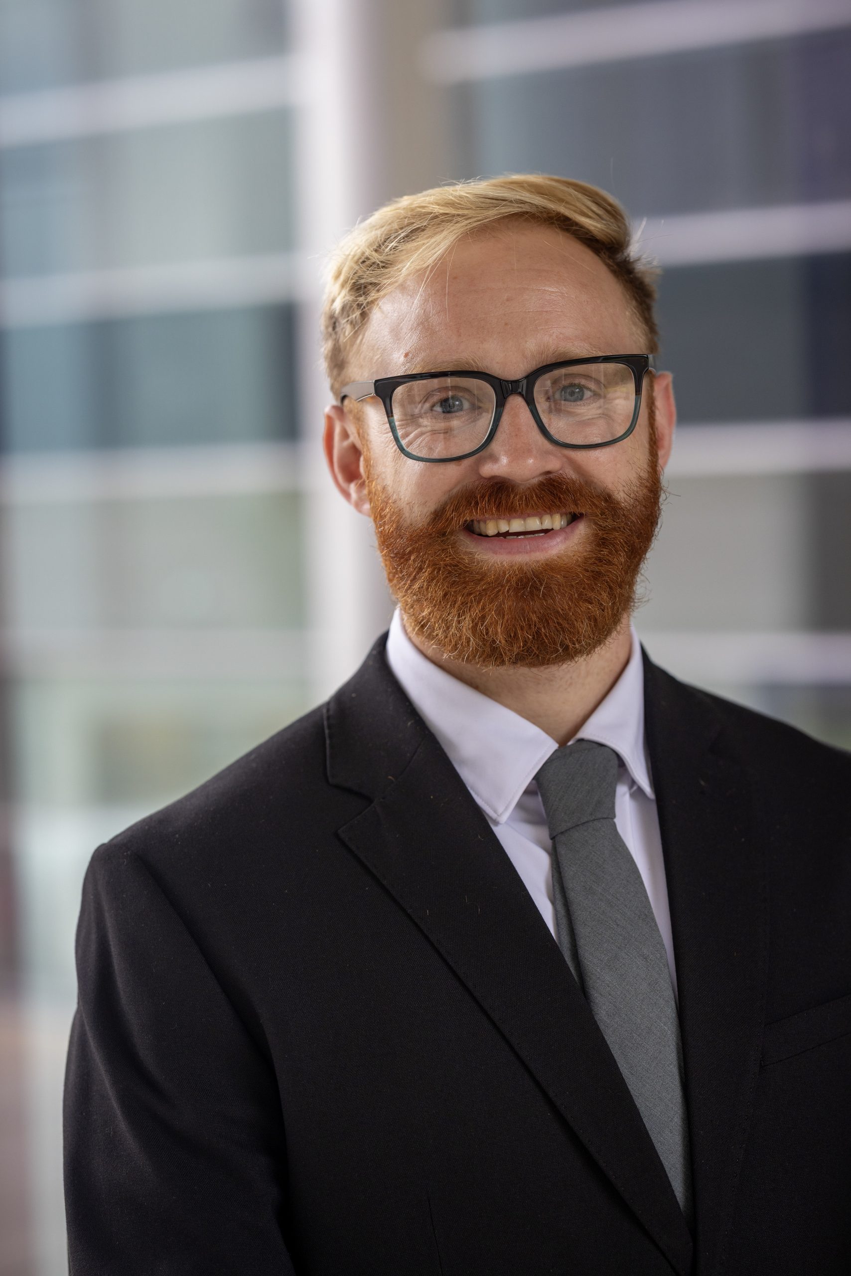 Person mit Brille, Anzug, Hemd und Krawatte.