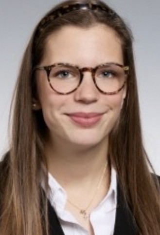 Person trägt eine Brille, ein Stirnband, eine Bluse, eine Jacke und eine Halskette.
