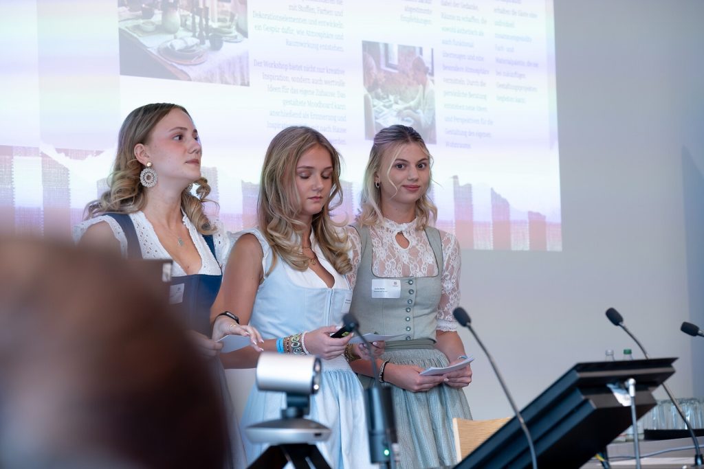 Drei Personen in traditioneller Tracht stehen mit Mikrofonen im Vordergrund und konzentrieren sich auf das Hauptprodukt oder die Idee, um die es gerade geht. Drei Personen in traditioneller Tracht stehen mit Mikrofonen im Vordergrund und konzentrieren sich auf das Hauptprodukt oder die Idee, um die es gerade geht.