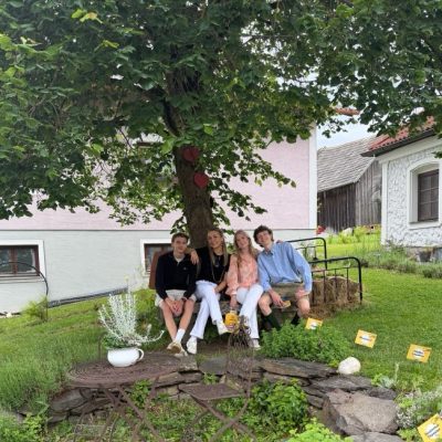 Eine Gruppe sitzt im Freien an einem Tisch mit Stühlen.