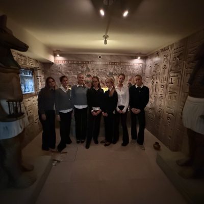 Acht Personen mit Statuen im ägyptischen Stil und Schnitzmustern an den Wänden.