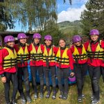 Eine Gruppe von Menschen, die Schwimmwesten und Helme tragen, steht beieinander und bereitet sich auf eine Wasseraktivität vor.