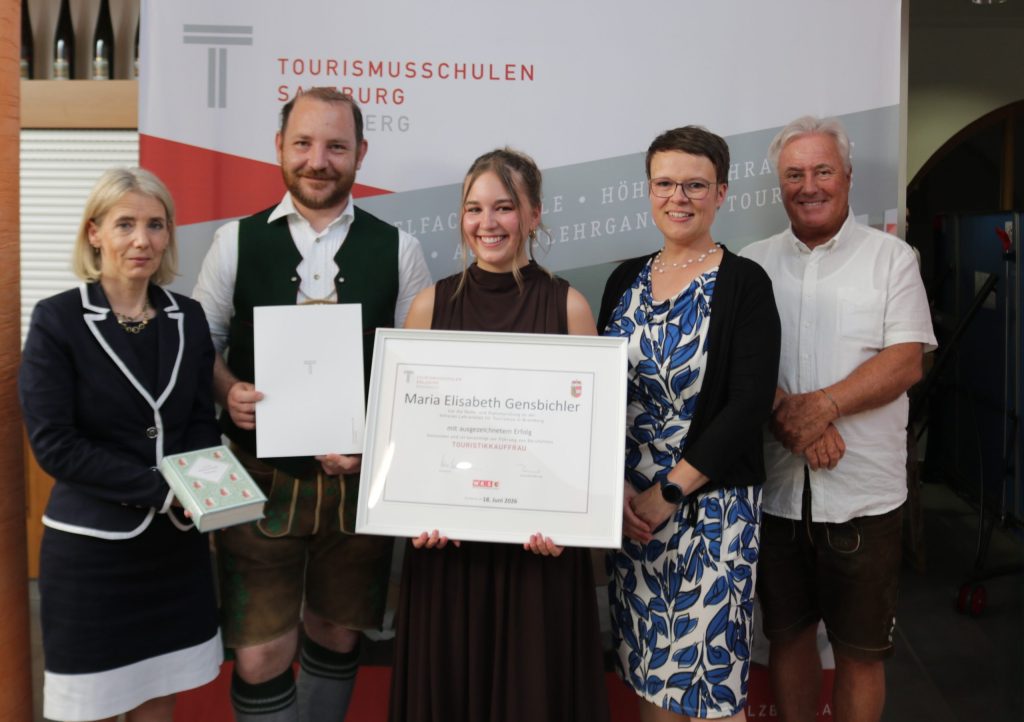 Fünf Personen bei einer Preisverleihung, in deren Mitte eine Urkunde für die Maturaklasse und Abschlussklasse 2025 ausgestellt ist.