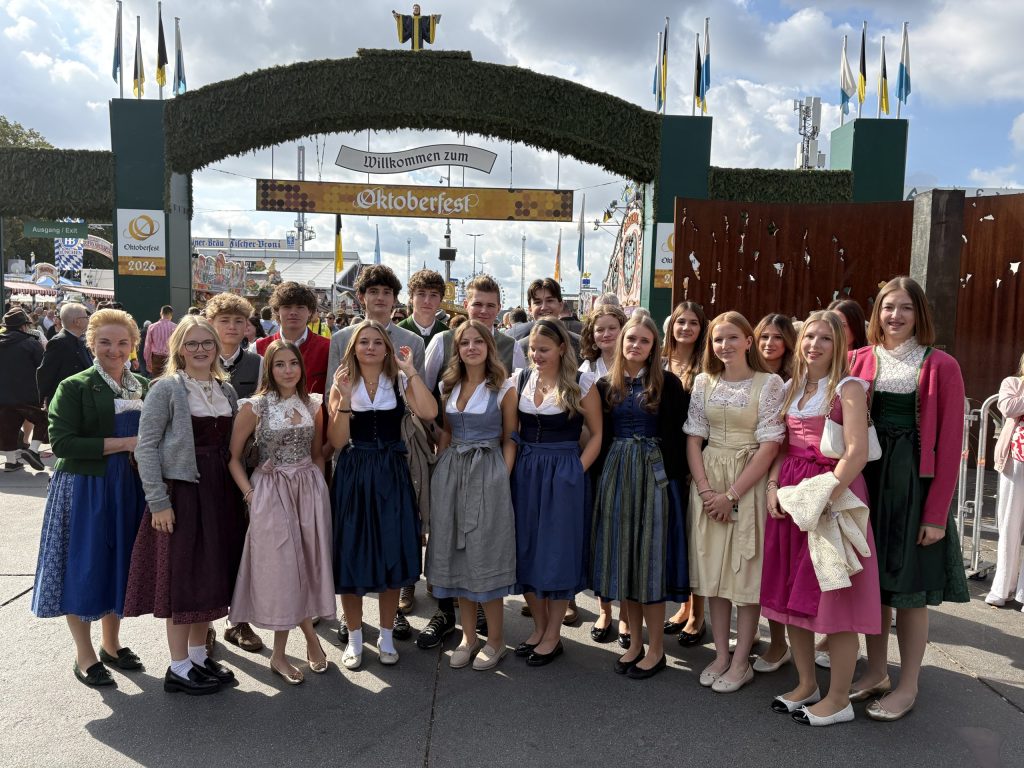 Menschen in traditioneller bayerischer Tracht auf dem Oktoberfest. Eine Gruppe in traditioneller bayerischer Tracht steht gemeinsam auf dem Oktoberfest und rückt damit die bayerische Tracht als Hauptprodukt in den Vordergrund.