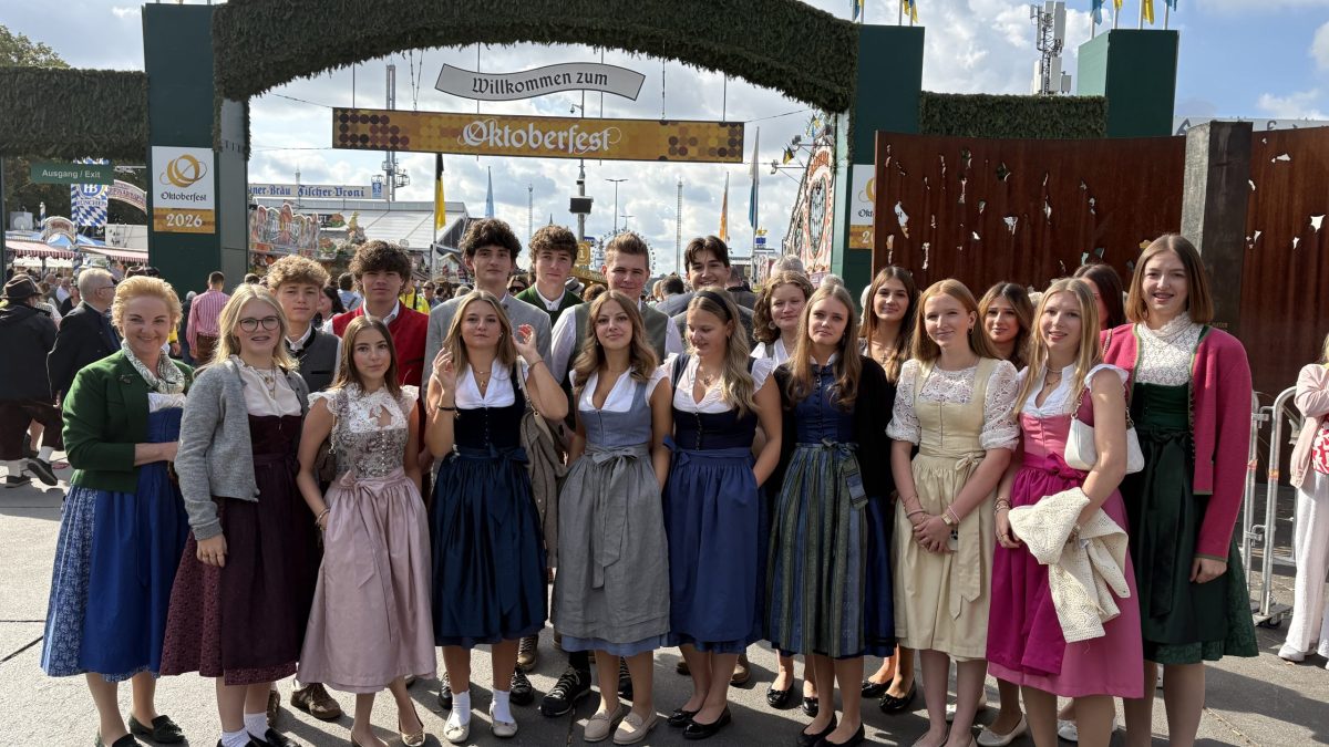 Eine Gruppe in traditioneller bayerischer Tracht steht gemeinsam auf dem Oktoberfest und rückt damit die bayerische Tracht als Hauptprodukt in den Vordergrund.