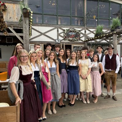 Menschen in traditioneller bayerischer Tracht mit Schnittmustern stehen zusammen und präsentieren das Produkt.
