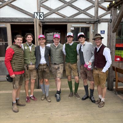 Eine Gruppe in traditioneller bayerischer Tracht und mit Hüten, die lächelt.