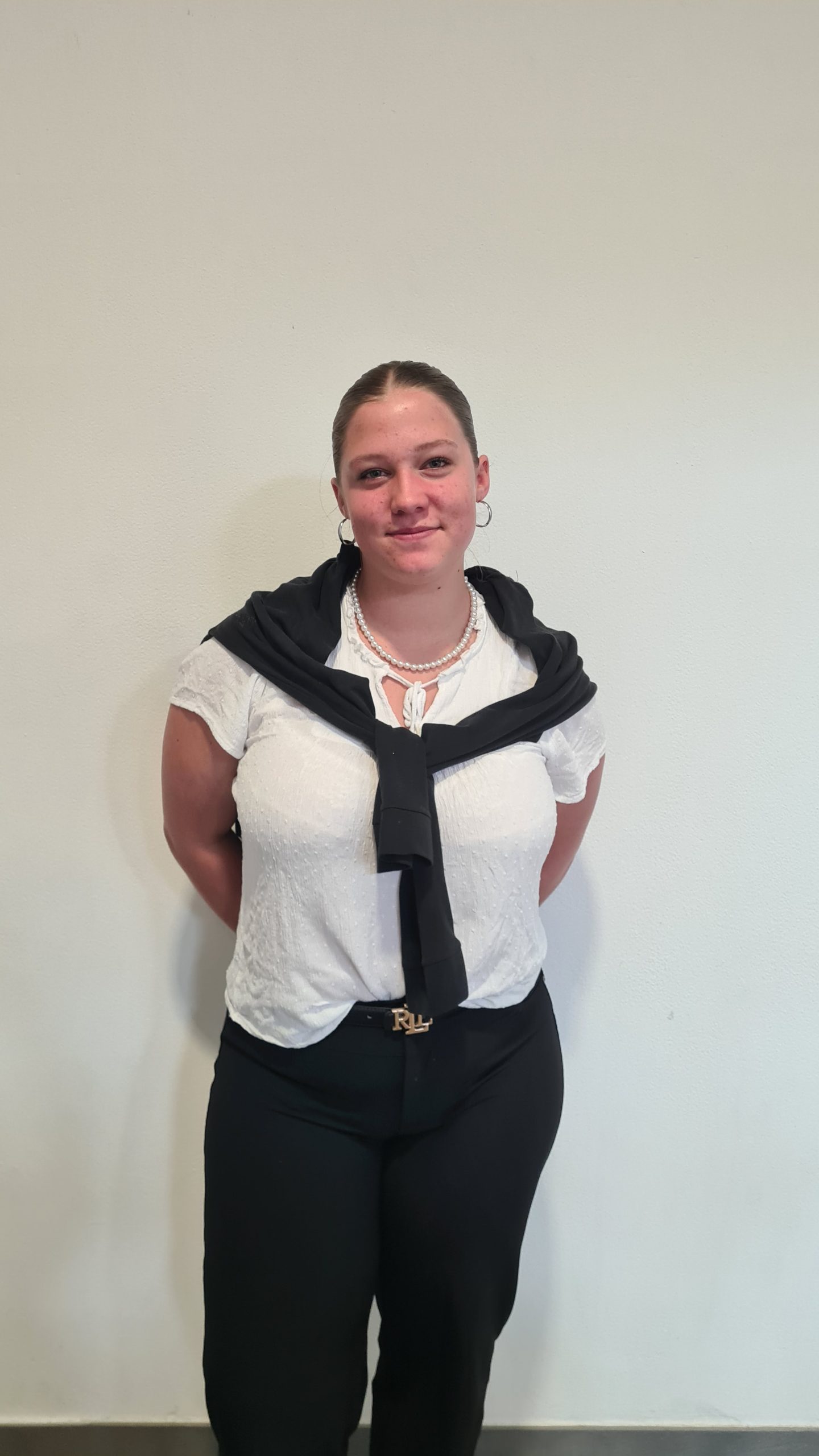 Bluse, Hose und Pullover über die Schultern drapiert.