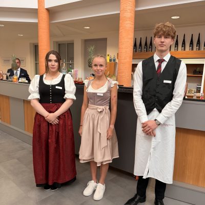 Tragen von traditioneller Kleidung, möglicherweise anlässlich der Vorprüfungen der Reife- und Diplomprüfungen 2025. Fokus nur auf Kleidungsstil und Produktpräsenz.