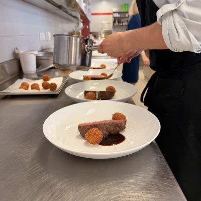 Das Essen wird mit einer Soße, einer Fleischscheibe und zwei gebratenen Bällchen für Vorprüfungen reife- und diplomprüfungen 2025 angerichtet.