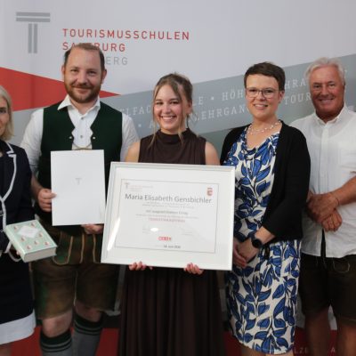 Fünf Personen bei einer Preisverleihung, in deren Mitte eine Urkunde für die Maturaklasse und Abschlussklasse 2025 ausgestellt ist.