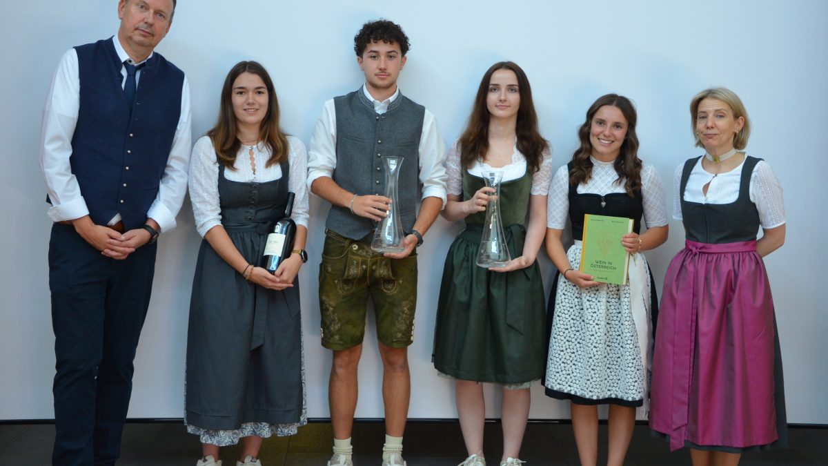 Sechs Personen, darunter die Gewinner des Wettbewerbs „Jungsommelier Österreich 2019“, stehen gemeinsam in traditioneller Tracht da, wobei vier von ihnen Auszeichnungen in den Händen halten.