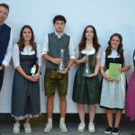 Sechs Personen, darunter die Gewinner des Wettbewerbs „Jungsommelier Österreich 2019“, stehen gemeinsam in traditioneller Tracht da, wobei vier von ihnen Auszeichnungen in den Händen halten.