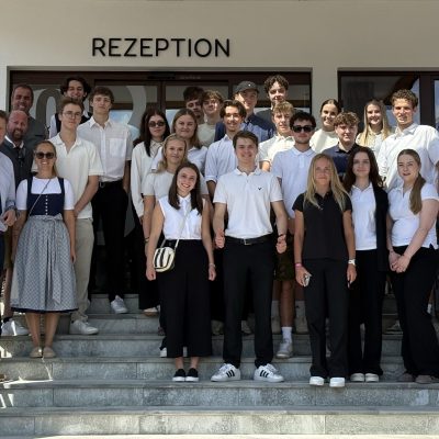 Gruppe von Jugendlichen und Erwachsenen vor der Rezeption eines Gebäudes